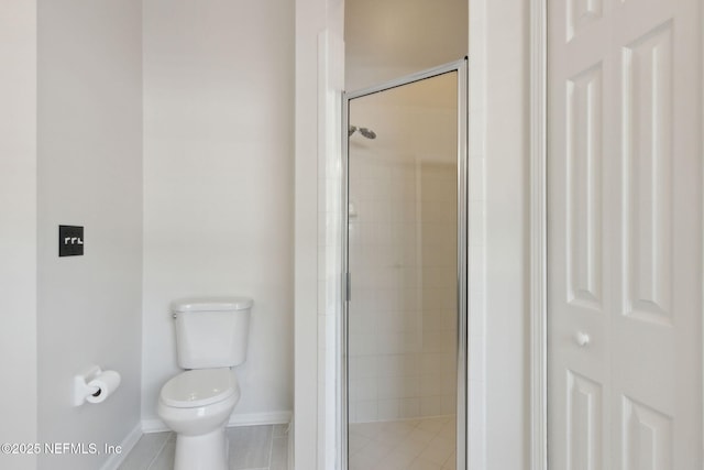 full bathroom featuring toilet, a stall shower, baseboards, and tile patterned floors