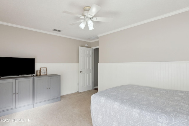 bedroom with visible vents, a ceiling fan, light colored carpet, a wainscoted wall, and ornamental molding