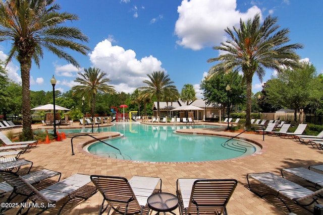 community pool with a patio area and fence