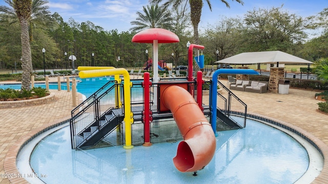 community jungle gym featuring a water play area, a community pool, and fence