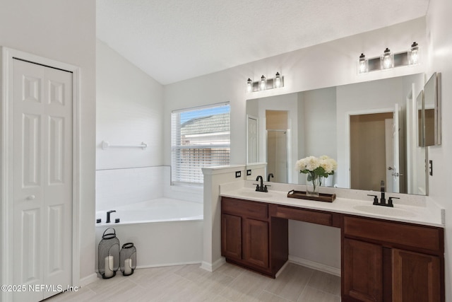 bathroom with a garden tub, a sink, a shower stall, and double vanity