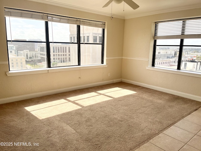 carpeted empty room featuring a healthy amount of sunlight, baseboards, crown molding, and tile patterned floors