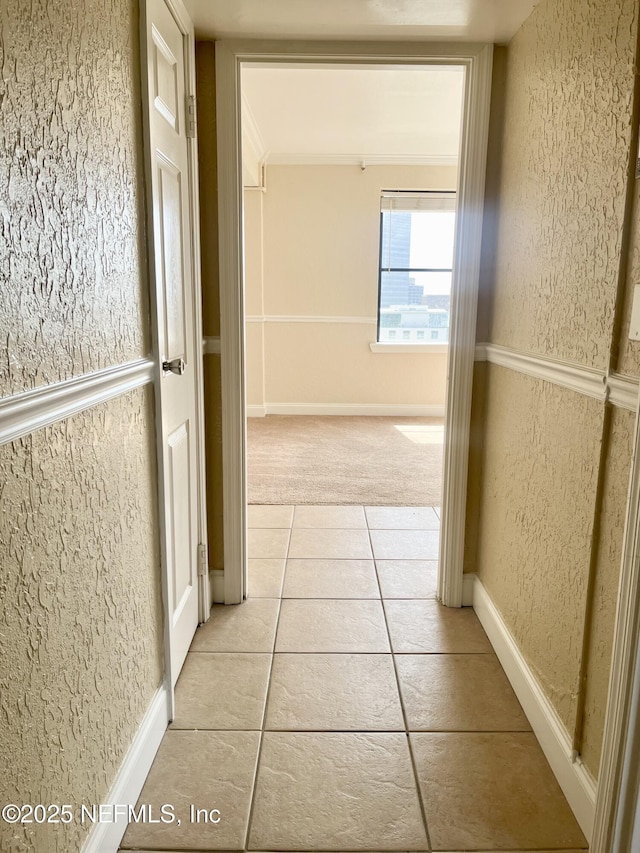 corridor with light tile patterned flooring and a textured wall