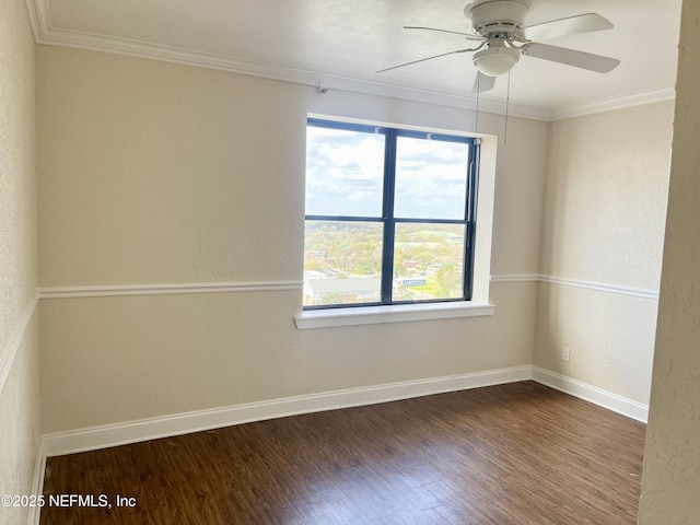 spare room featuring ornamental molding, baseboards, and wood finished floors