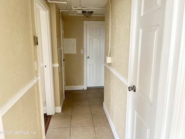 hall with light tile patterned floors and a textured wall