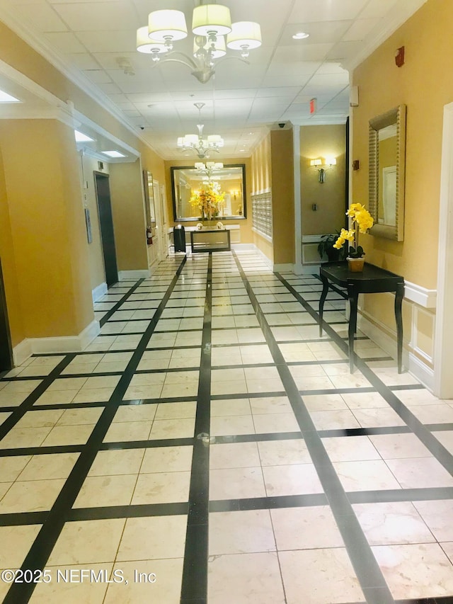 corridor featuring crown molding, baseboards, a notable chandelier, and tile patterned floors