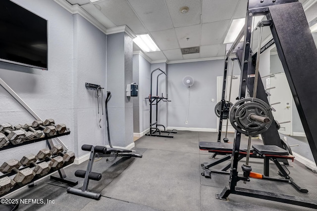 gym with ornamental molding, a drop ceiling, and baseboards