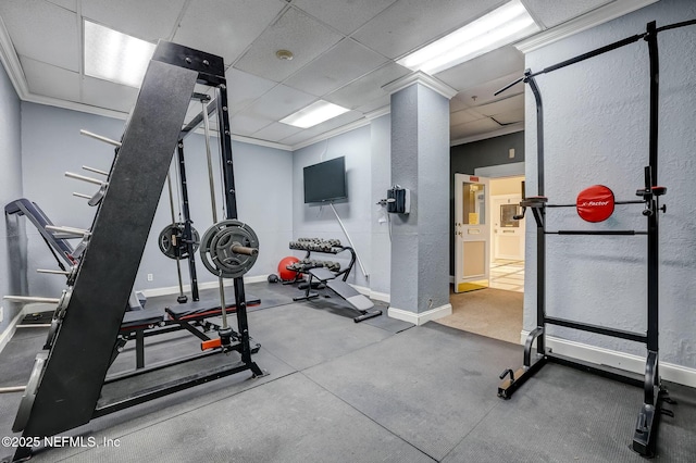 exercise area with ornamental molding, a paneled ceiling, and baseboards