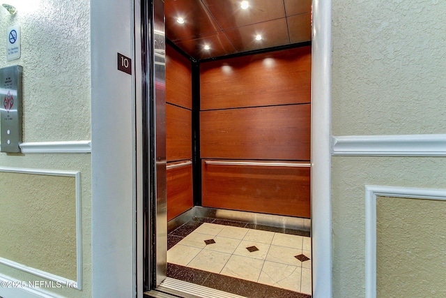 details featuring recessed lighting, elevator, and a textured wall