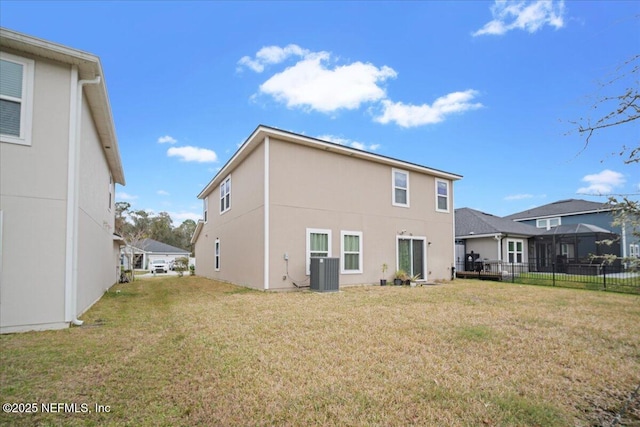 back of property with stucco siding, central AC, a yard, and fence