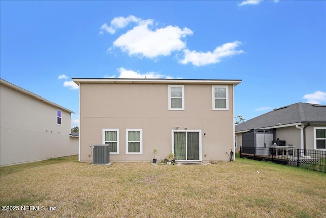 back of property with central air condition unit, fence, a lawn, and stucco siding