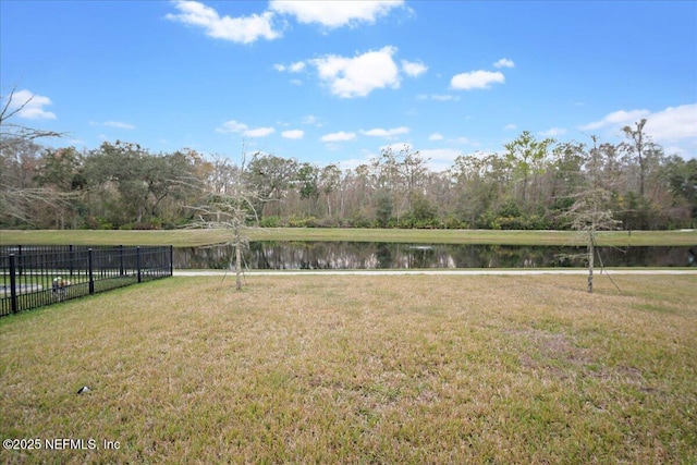 view of community featuring a lawn, a water view, and fence