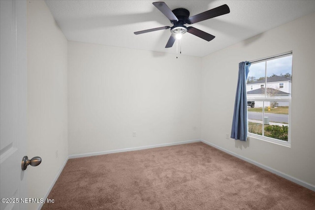 carpeted spare room featuring a wealth of natural light, a textured ceiling, and baseboards