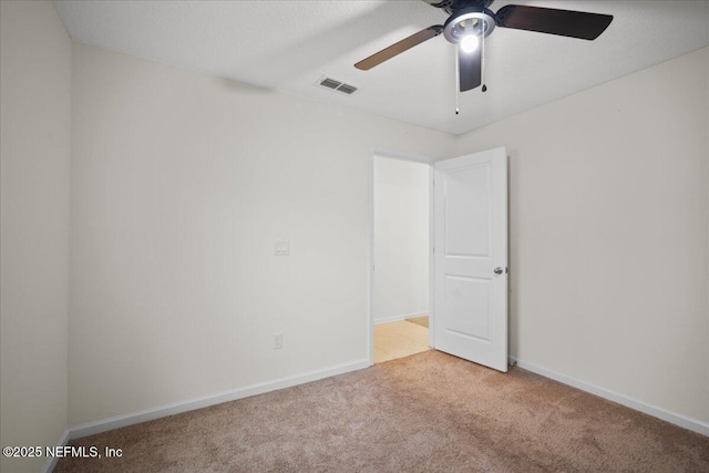 unfurnished room with baseboards, a ceiling fan, visible vents, and light colored carpet