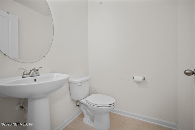 half bath with tile patterned flooring, toilet, and baseboards