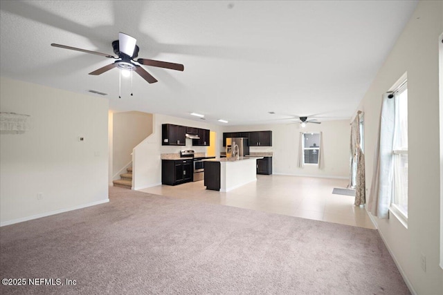 unfurnished living room with visible vents, stairway, a ceiling fan, light carpet, and baseboards