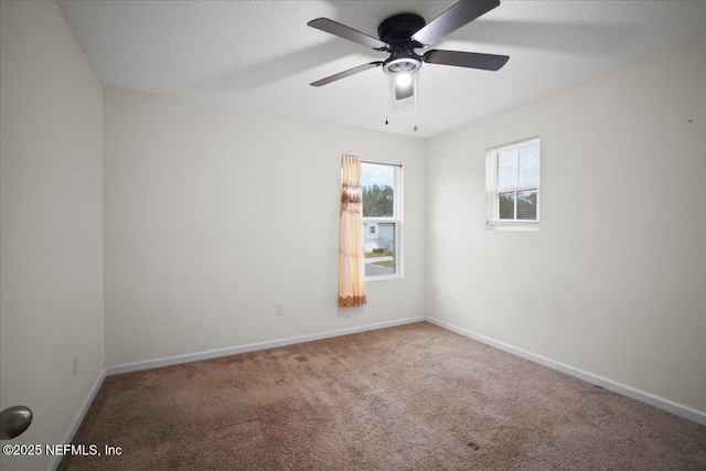 carpeted empty room with a textured ceiling, a ceiling fan, and baseboards