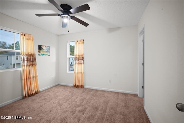 carpeted empty room featuring a textured ceiling, ceiling fan, plenty of natural light, and baseboards