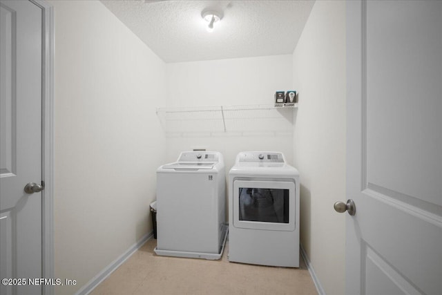 clothes washing area featuring a textured ceiling, laundry area, independent washer and dryer, and baseboards