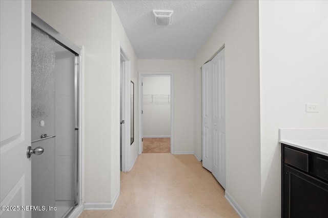 corridor with baseboards and a textured ceiling