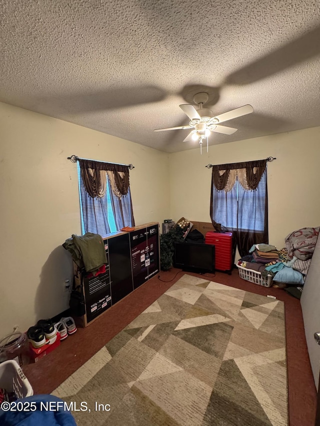 bedroom featuring carpet flooring, ceiling fan, a textured ceiling, and multiple windows