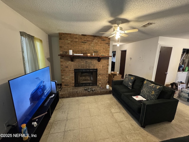 living room featuring a ceiling fan, visible vents, a fireplace, and a textured ceiling