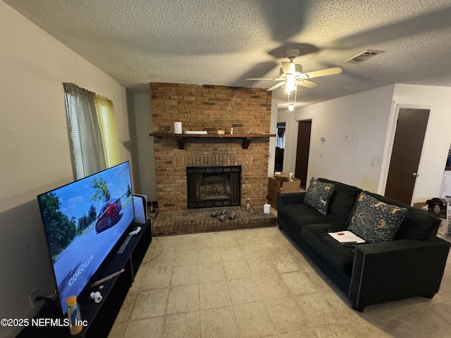 living area with a brick fireplace, ceiling fan, visible vents, and a textured ceiling