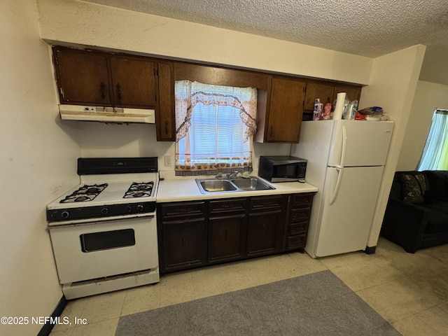 kitchen featuring light floors, a sink, a textured ceiling, white appliances, and under cabinet range hood