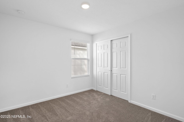 unfurnished bedroom with carpet floors, a closet, and baseboards