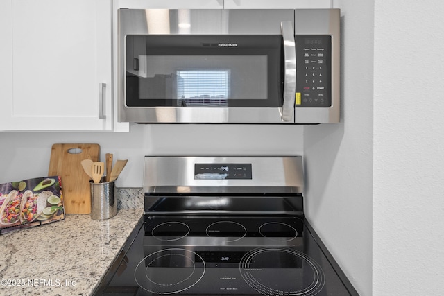 interior details featuring white cabinets, light stone countertops, and stainless steel appliances