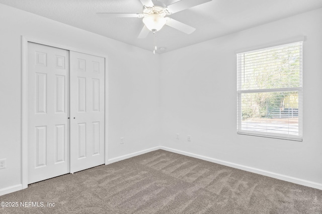 unfurnished bedroom featuring a closet, carpet floors, baseboards, and a ceiling fan