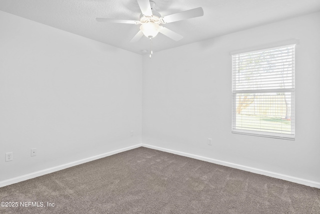 unfurnished room with a ceiling fan, baseboards, dark colored carpet, and a textured ceiling