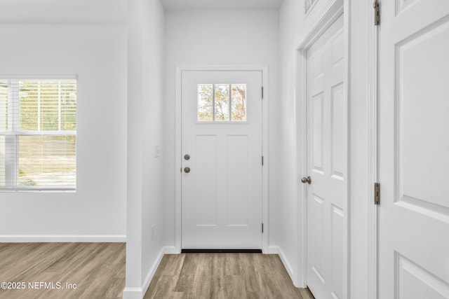 doorway to outside featuring light wood-type flooring, baseboards, and a healthy amount of sunlight