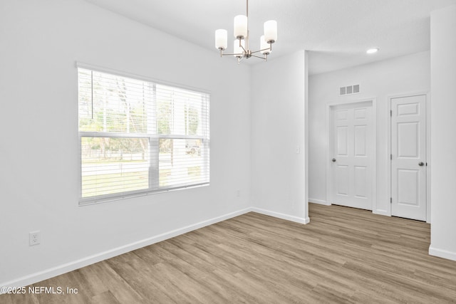 spare room featuring visible vents, baseboards, light wood-style floors, and a chandelier