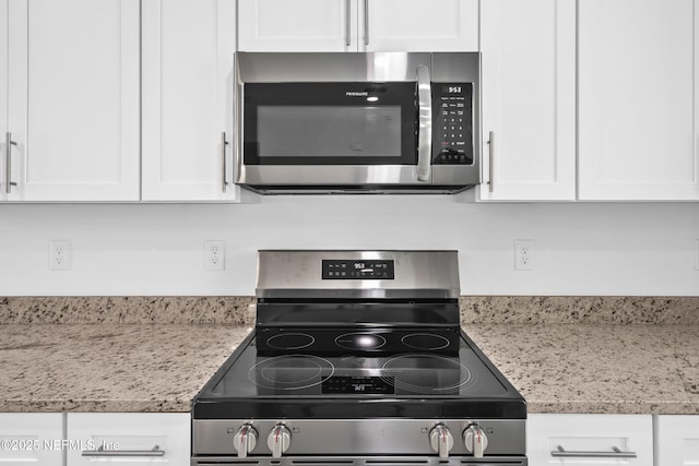 kitchen with light stone countertops, appliances with stainless steel finishes, and white cabinets