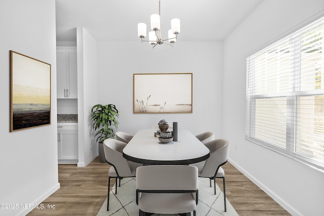 dining area with a notable chandelier, light wood-style flooring, and baseboards