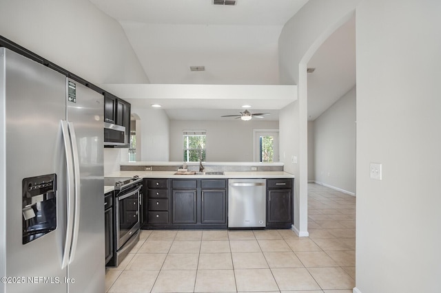 kitchen featuring light tile patterned floors, lofted ceiling, stainless steel appliances, light countertops, and a sink