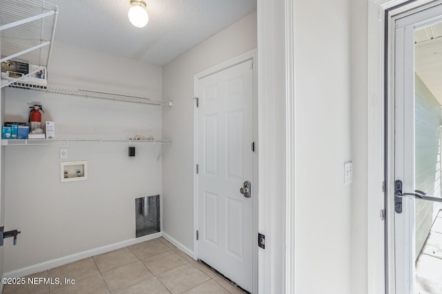 clothes washing area with laundry area, baseboards, light tile patterned floors, and washer hookup