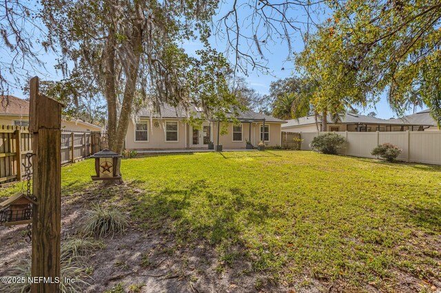 back of property with stucco siding, a fenced backyard, and a yard