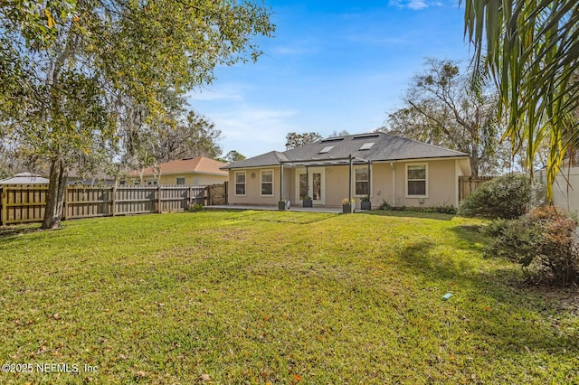 back of house with a fenced backyard, a lawn, and stucco siding