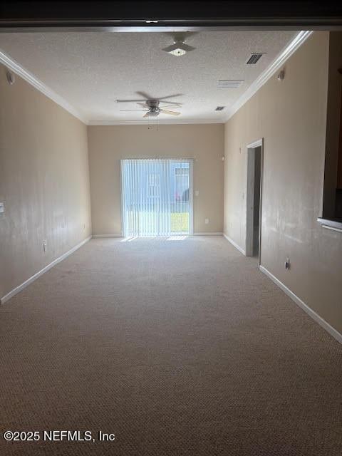 carpeted spare room featuring visible vents, a textured ceiling, baseboards, and crown molding