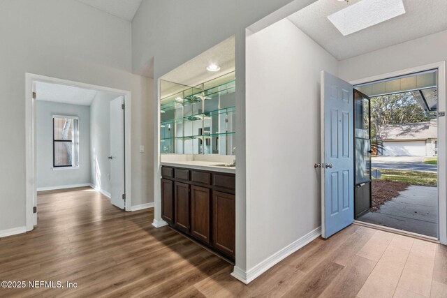 entryway with a skylight, baseboards, and wood finished floors