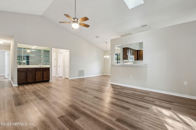 unfurnished living room featuring baseboards, visible vents, wood finished floors, and ceiling fan with notable chandelier