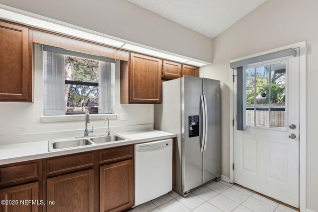 kitchen with dishwasher, stainless steel fridge, a sink, and a wealth of natural light