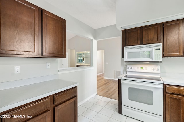 kitchen featuring light tile patterned floors, white appliances, visible vents, baseboards, and light countertops