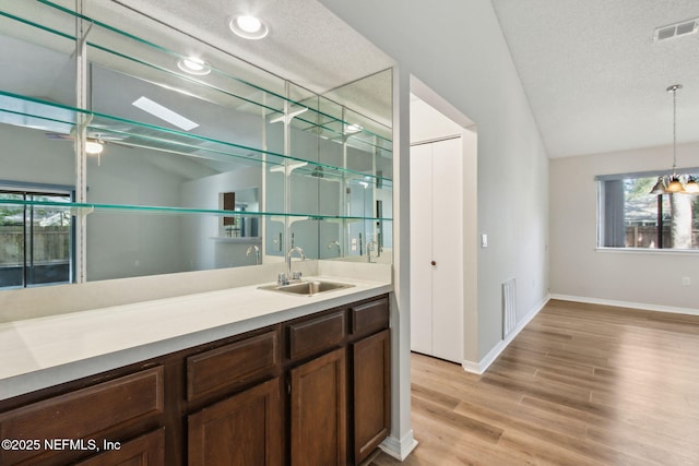 bar featuring vaulted ceiling, visible vents, a sink, and a textured ceiling