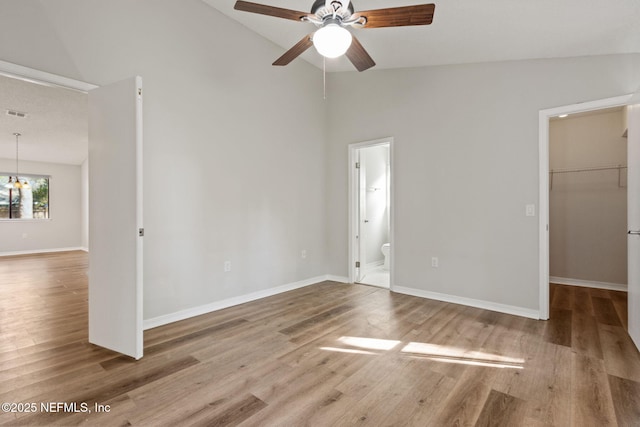 unfurnished bedroom with a spacious closet, wood finished floors, and baseboards