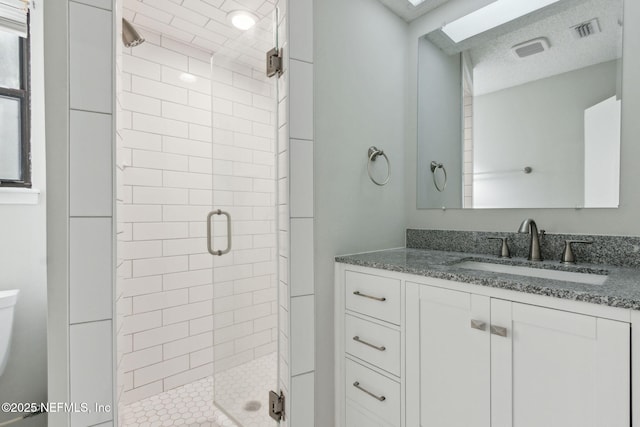 bathroom featuring a textured ceiling, toilet, vanity, visible vents, and a shower stall