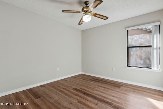 empty room featuring a textured ceiling, baseboards, and wood finished floors