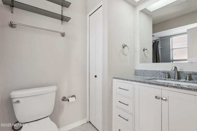 bathroom featuring vanity, toilet, and baseboards